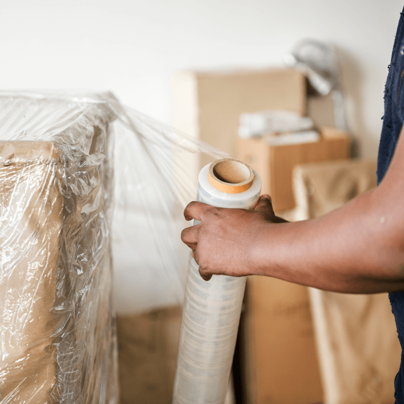 Interracial couple smiling while moving with cardboard boxes on a sunny day.