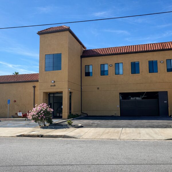 Interracial couple smiling while moving with cardboard boxes on a sunny day.